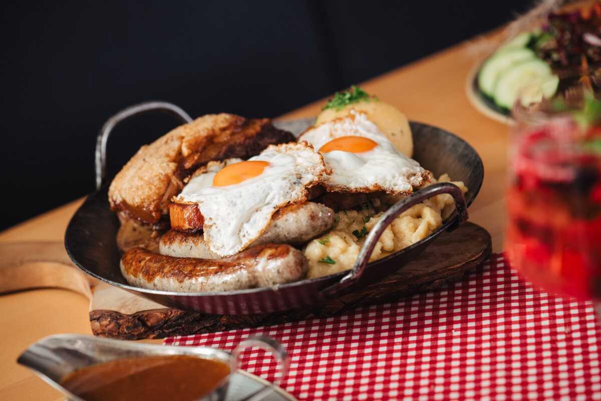 A Franconian skillet with sausages, fried eggs, schnitzel and side dishes on the checked tablecloth.