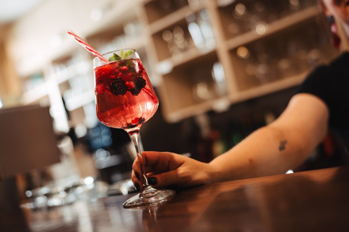 Nadine serves a red drink with berries and mint across the bar at Café Zeis.