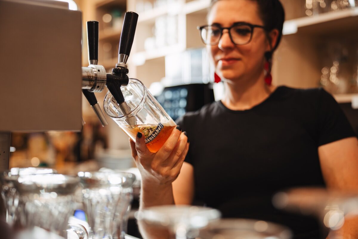 Nadine zapft an der Theke des Café Zeis ein Glas Bier.