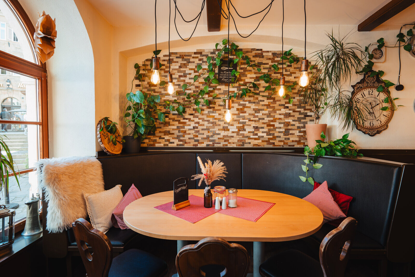 A cosy corner with wooden tables, cushions and a lamp in the living room at Café Zeis.