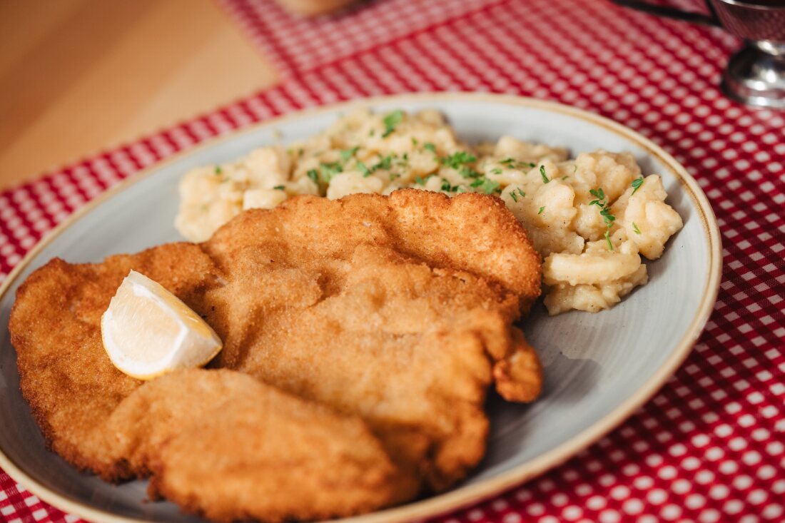 Freshly breaded schnitzel with potato salad on the red-and-white checked tablecloth at Restaurant Café Zeis.