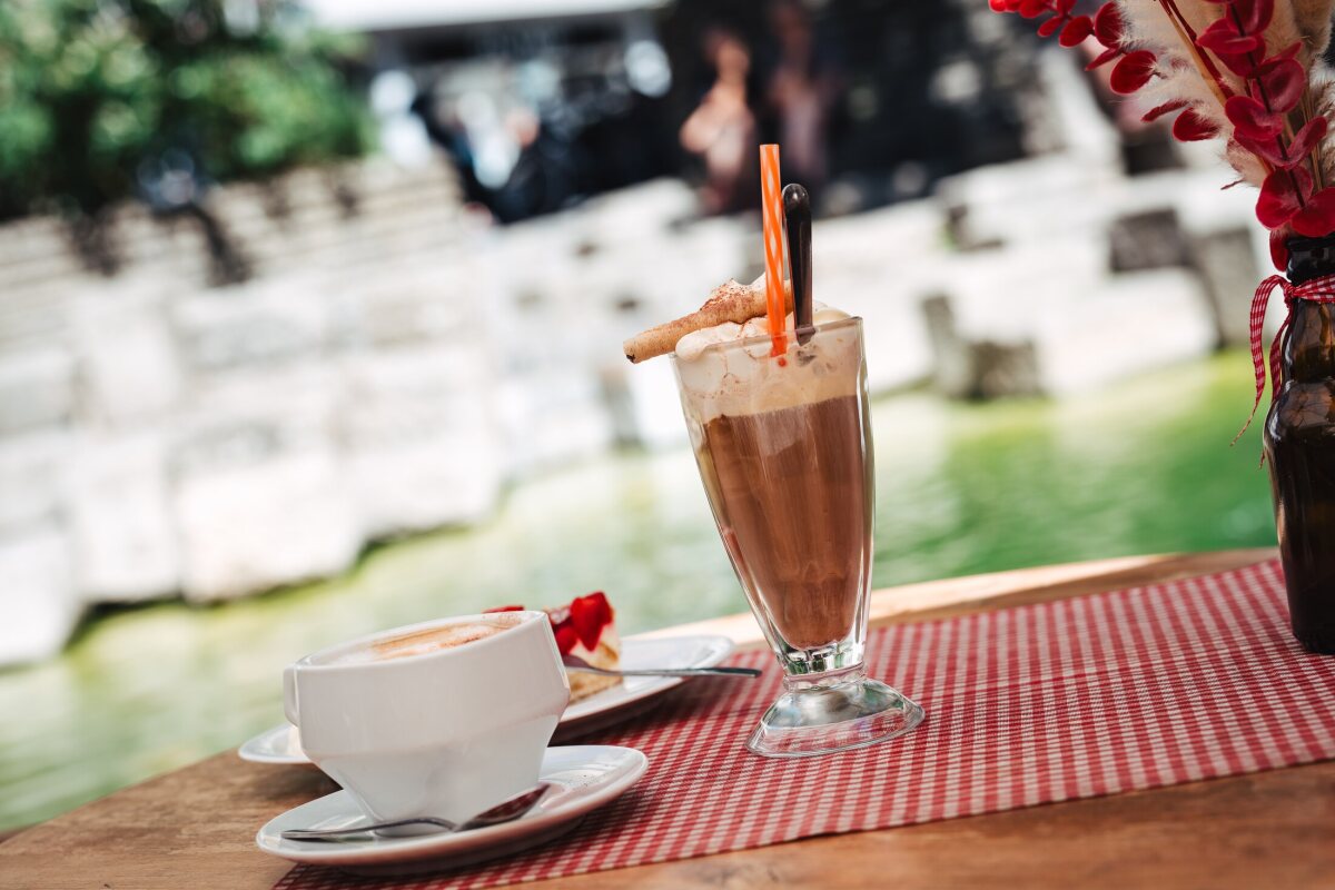 Coffee and a cold drink topped with whipped cream on the checked tablecloth by the fountain.