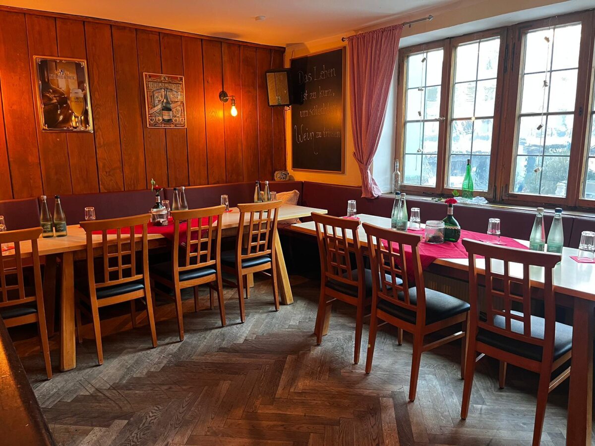 Die Weinstube im Obergeschoss mit Holztischen, Holzvertäfelung und großer Fensterfront, für eine Besprechung vorbereitet.
